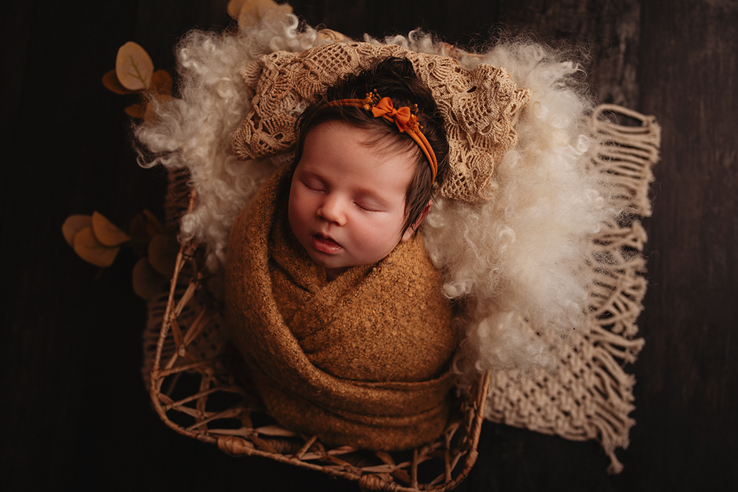 Newborn baby in yellow wrap in basket