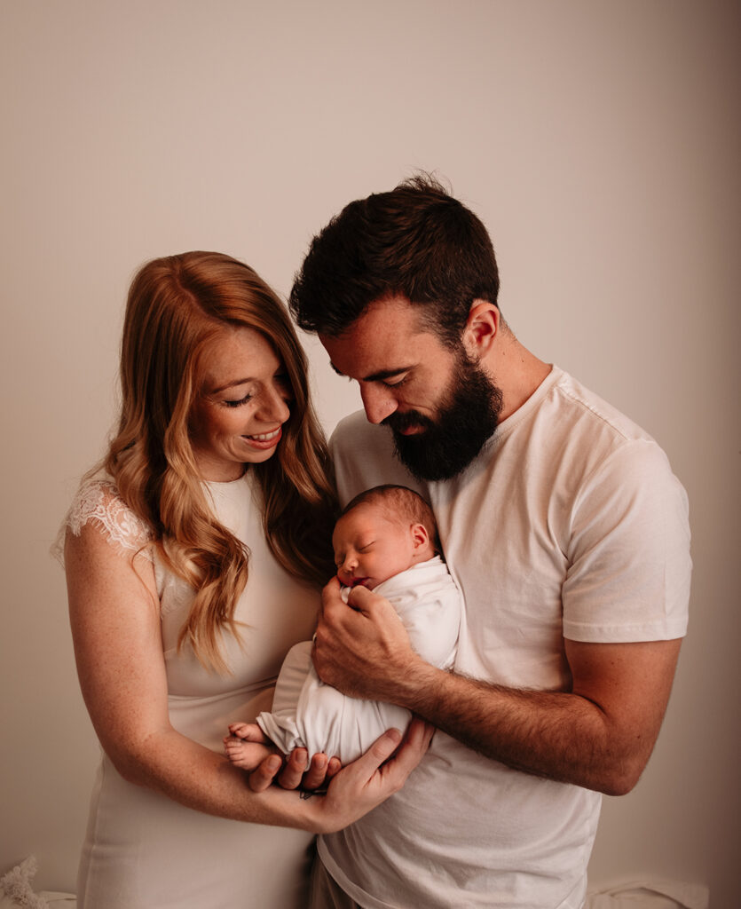 family with newborn baby photo in white